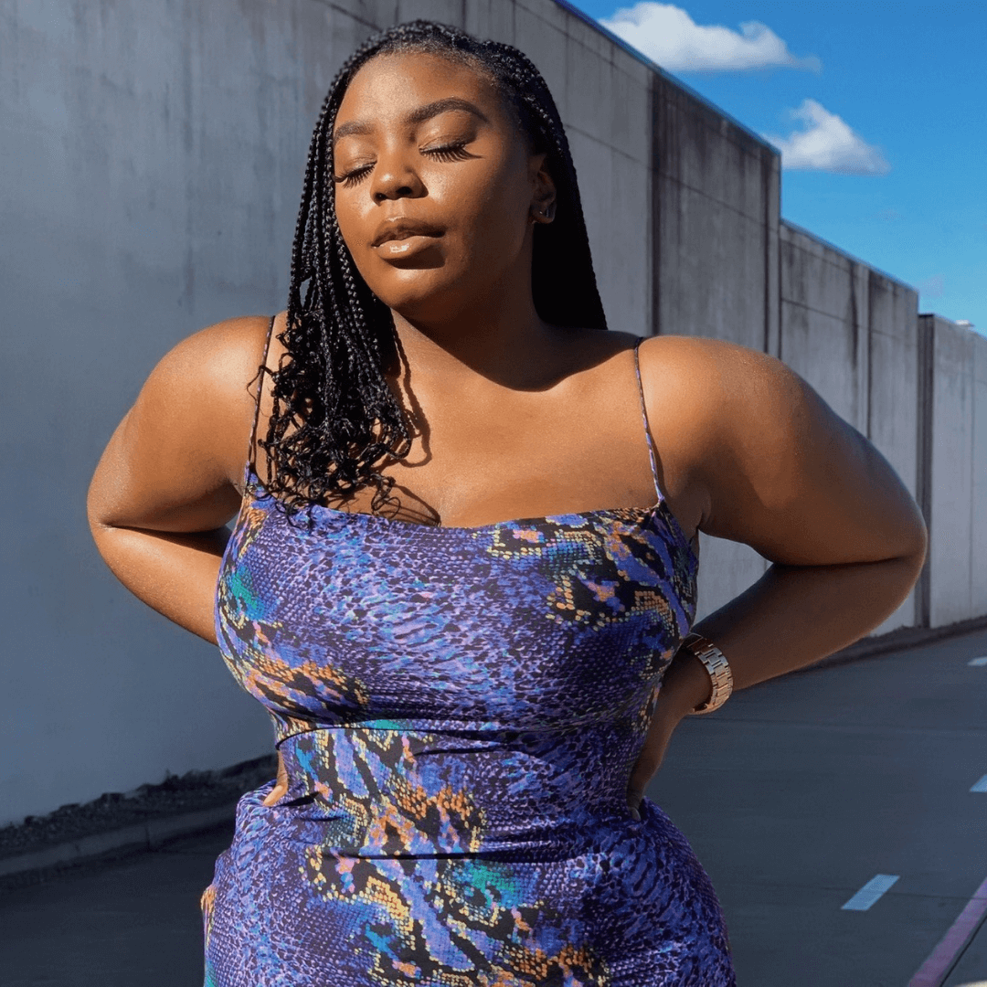 dark skinned girl in braids in snakeskin dress using black boob tape